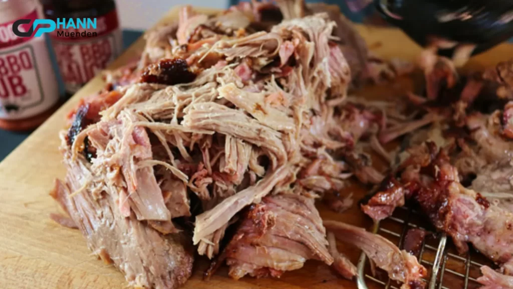 A smoked pork butt resting in a glass dish after hours of slow smoking, revealing its rich, dark bark. How long to smoke a pork butt for juicy tenderness?