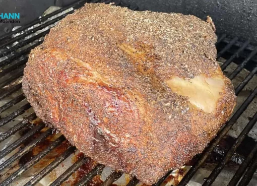 A perfectly seasoned pork butt cooking on a smoker rack, showcasing the ideal texture and crust formation. How long to smoke a pork butt for such results?